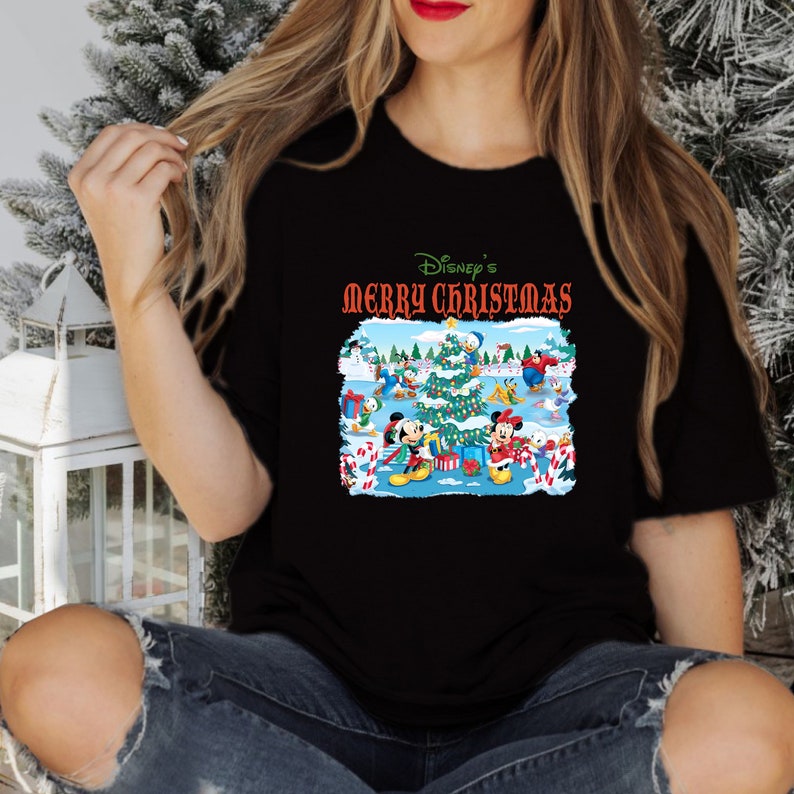 May include: Black t-shirt with a colorful Christmas scene featuring Mickey Mouse, Minnie Mouse, Donald Duck, Goofy, and Pluto. The text "Disney's Merry Christmas" is printed in red and white on the shirt.