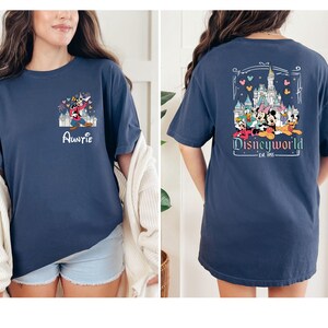 May include: A navy blue t-shirt with a graphic of Mickey Mouse and friends in front of Cinderella's Castle. The front of the shirt says "Auntie" and the back says "Disneyworld - Est. 1955".