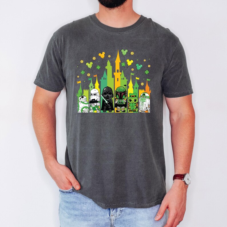 Puede incluir: Camiseta gris oscuro con un gr&aacute;fico colorido de personajes de Star Wars frente a un castillo. El dise&ntilde;o incluye elementos verdes, amarillos y blancos, con tr&eacute;boles y orejas de Mickey Mouse. La camiseta es c&oacute;moda e informal.