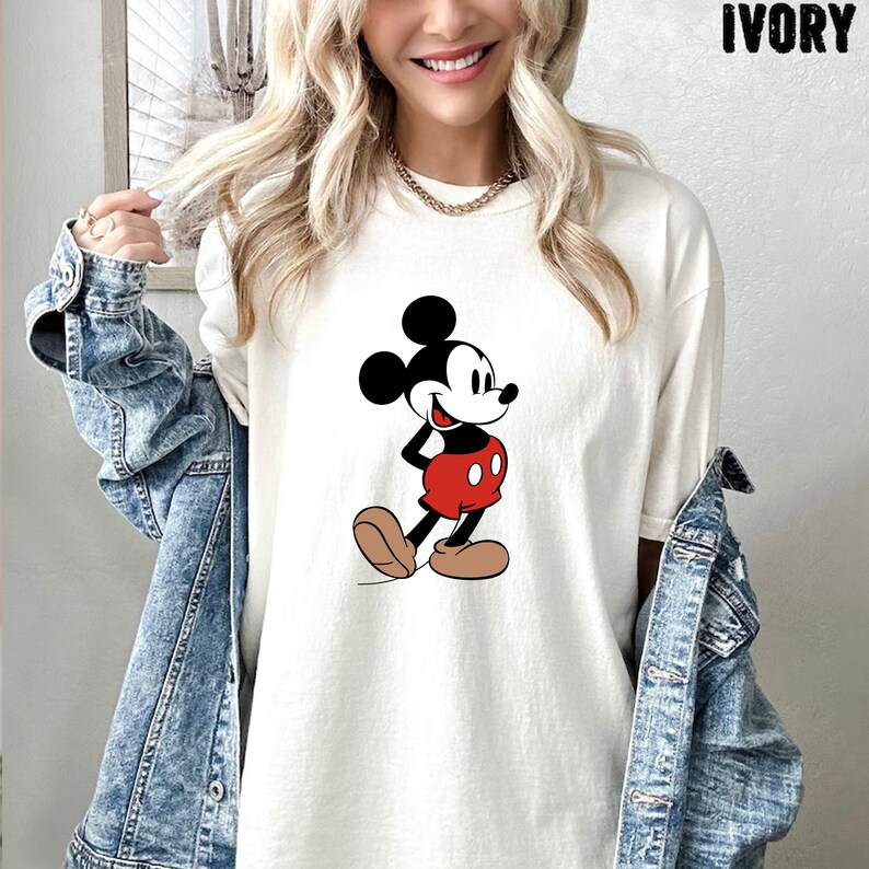 Op de afbeelding: Wit T-shirt met een cartoon afbeelding van Mickey Mouse in een rood en zwart outfit. Het shirt heeft een relaxed fit en een ronde hals.