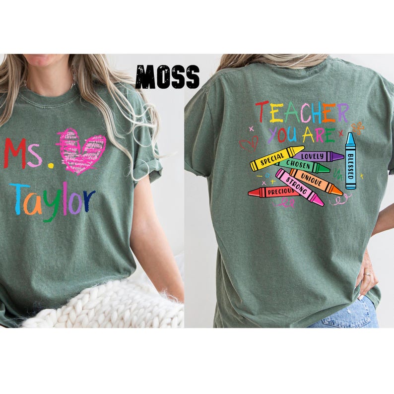 May include: A moss green t-shirt with the text "Ms. Taylor" in colorful letters and a pink heart graphic. The back of the shirt features the words "Teacher You Are" with crayon illustrations and positive adjectives.