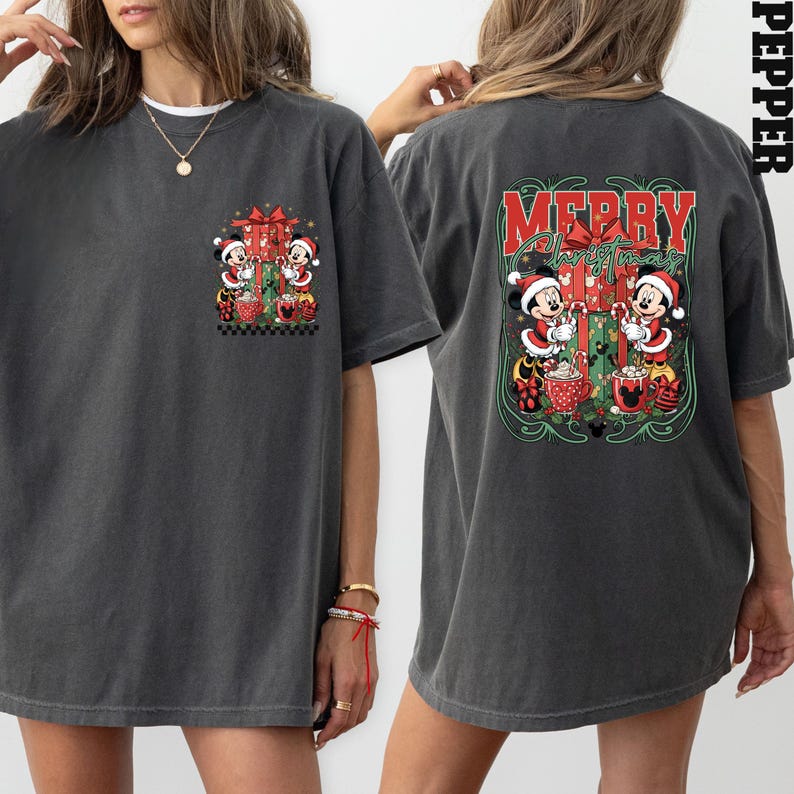 May include: Dark grey t-shirt with a Christmas design featuring Mickey and Minnie Mouse. The front has a small graphic, while the back displays a larger "Merry Christmas" design with the characters, candy canes, and gifts.