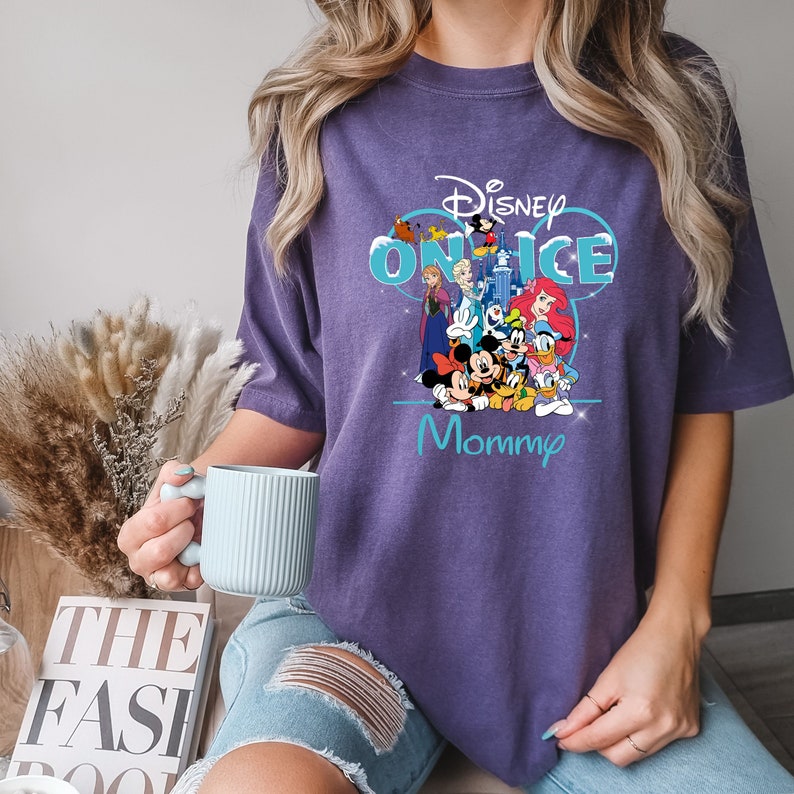 May include: Purple t-shirt with a graphic of Disney characters on ice, including Mickey Mouse, Minnie Mouse, Donald Duck, Goofy, and others. The text "Disney On Ice Mommy" is printed on the shirt.