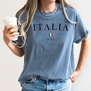 May include: A blue t-shirt with the word "ITALIA" printed in black, with the Italian flag and the word "ITALY" underneath.