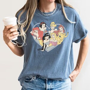 Pu&ograve; includere: Una maglietta blu con un design a forma di cuore che presenta sette principesse Disney: Ariel, Biancaneve, Jasmine, Aurora, Cenerentola, Belle e Rapunzel.