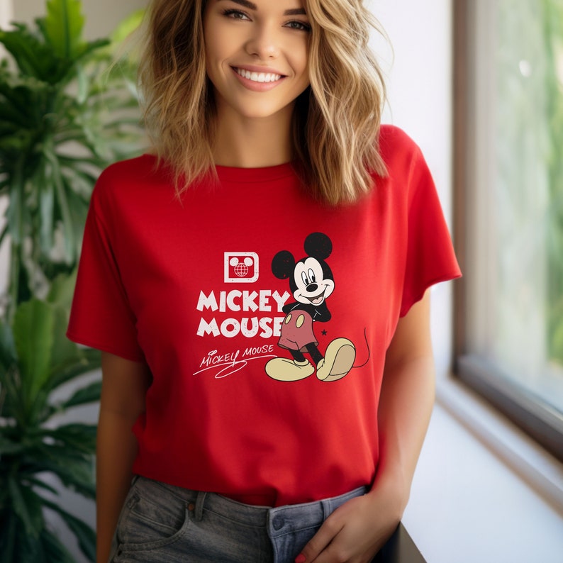 May include: Red t-shirt with a Mickey Mouse graphic and the text "Mickey Mouse" in white. The Mickey Mouse graphic is in a vintage style and features Mickey Mouse with his signature red shorts and yellow shoes.