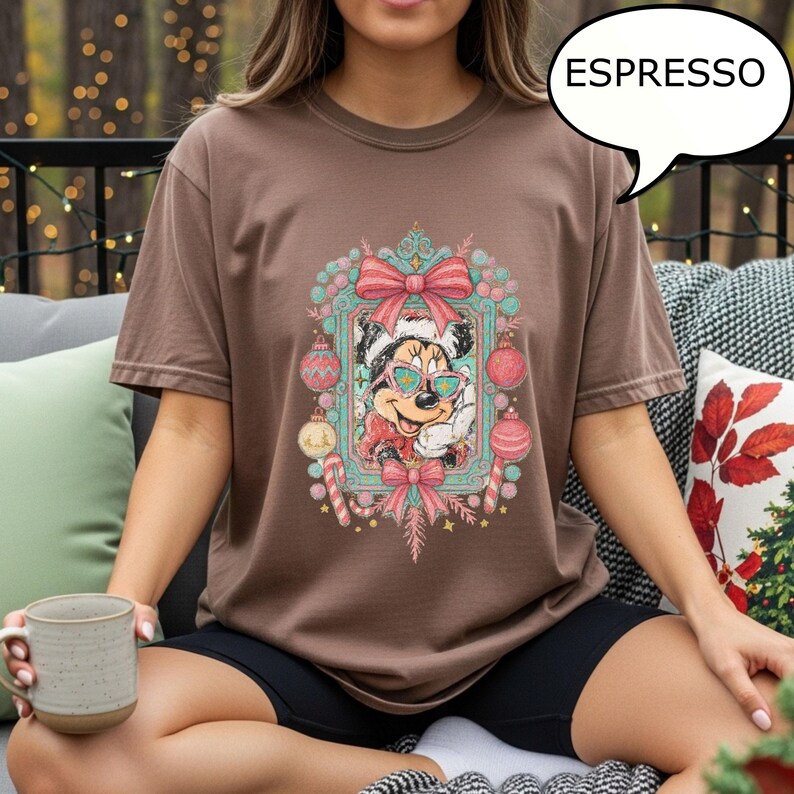 Puede incluir: Camiseta color espresso con un dise&ntilde;o festivo de Minnie Mouse. El dise&ntilde;o incluye una imagen enmarcada de Minnie con gafas de sol y un gorro de Pap&aacute; Noel, rodeada de adornos navide&ntilde;os y bastones de caramelo. La palabra "ESPRESSO" est&aacute; en una burbuja.