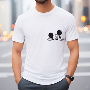 May include: A white t-shirt with a black Mickey Mouse graphic peeking over the edge of the shirt.