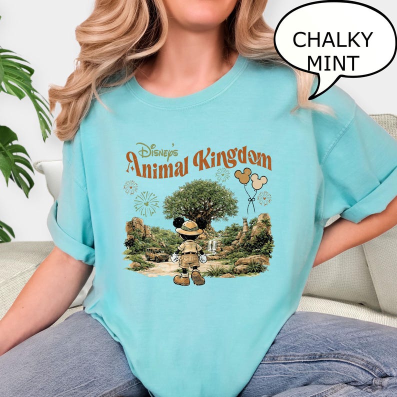 May include: A light blue t-shirt with the text "CHALKY MINT" in a speech bubble. The shirt features a graphic of Mickey Mouse in safari attire in front of a tree and the words "Disney's Animal Kingdom".