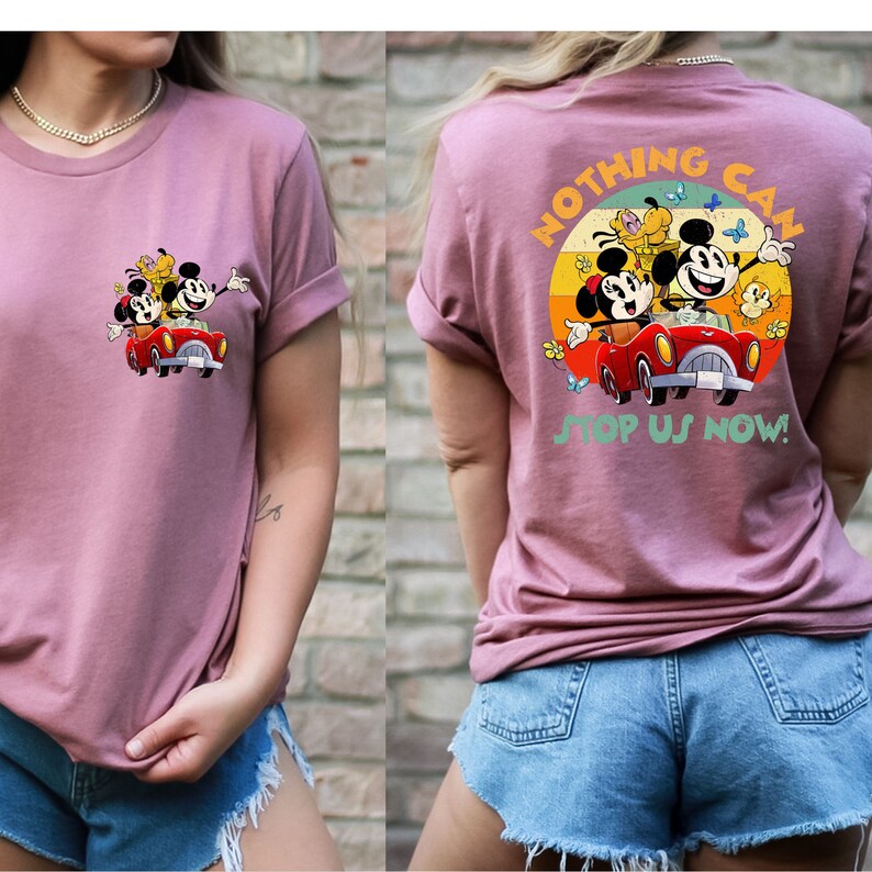 以下が含まれることがあります： ピンクのTシャツに、ミッキーマウス、ミニーマウス、プルートが赤い車に乗っているヴィンテージスタイルのグラフィックがプリントされています。グラフィックはシャツの後ろにあり、「Nothing Can Stop Us Now!」という文字が黄色と緑のフォントで書かれています。