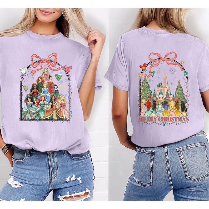 May include: A lilac t-shirt with a graphic of Disney princesses within a decorative arch and bow. The back displays a castle, Christmas trees, and the words "MERRY CHRISTMAS". The shirt is a comfortable, casual style.