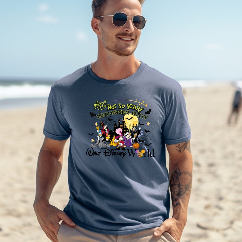 May include: A blue t-shirt with a graphic of Mickey Mouse and friends celebrating Halloween at Walt Disney World. The text on the shirt reads "Mickey's Not So Scary Halloween Party".
