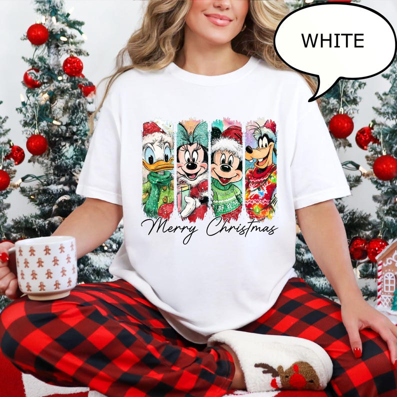 Puede incluir: Camiseta blanca con Donald Duck, Minnie Mouse, Mickey Mouse y Goofy con atuendos navide&ntilde;os. Las palabras "Merry Christmas" est&aacute;n escritas debajo de los personajes. La camiseta forma parte de un tema navide&ntilde;o.