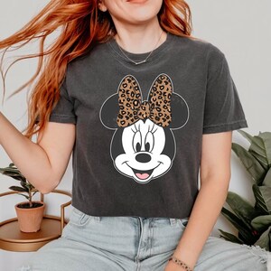 May include: A black cropped t-shirt with a cartoon image of Minnie Mouse. Minnie Mouse is wearing a leopard print bow.