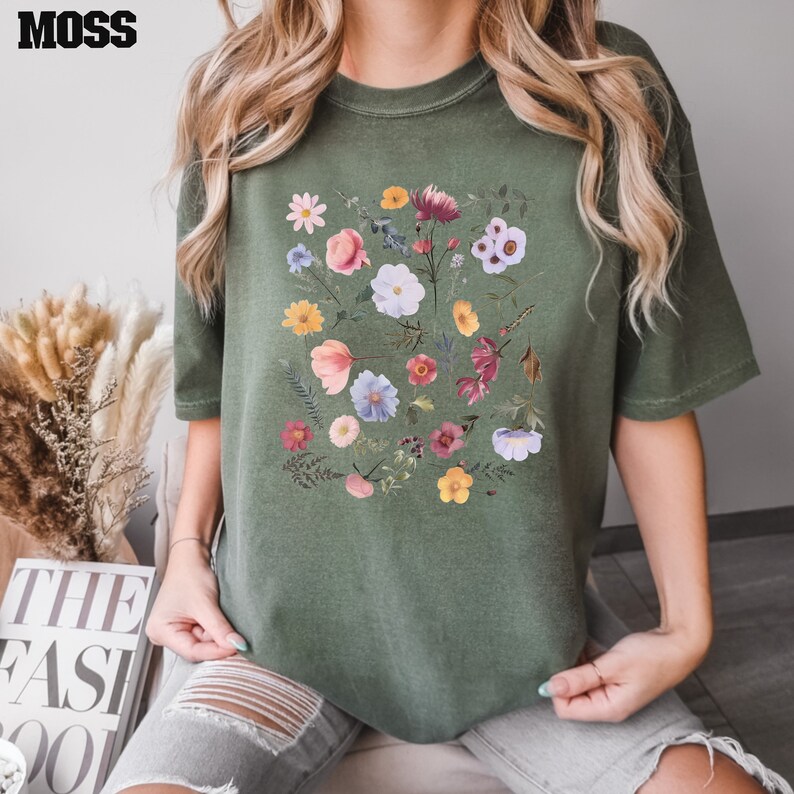 May include: A green t-shirt with a floral print featuring a variety of colorful flowers and leaves.