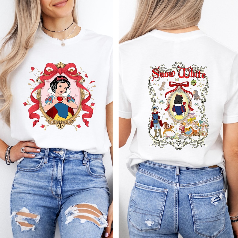 May include: White t-shirt featuring a Snow White graphic on the front and back. The front design shows Snow White holding an apple within a red ribbon frame. The back design includes the words "Snow White" and other characters.