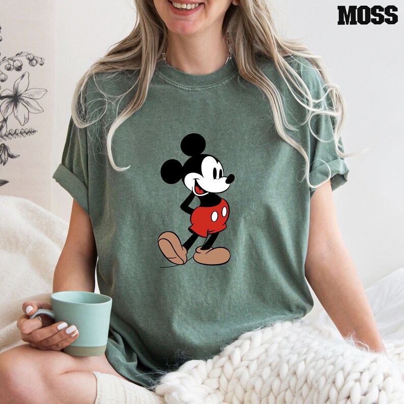 Op de afbeelding: Een groen T-shirt met een vintage cartoon afbeelding van Mickey Mouse in een rood-zwarte outfit.