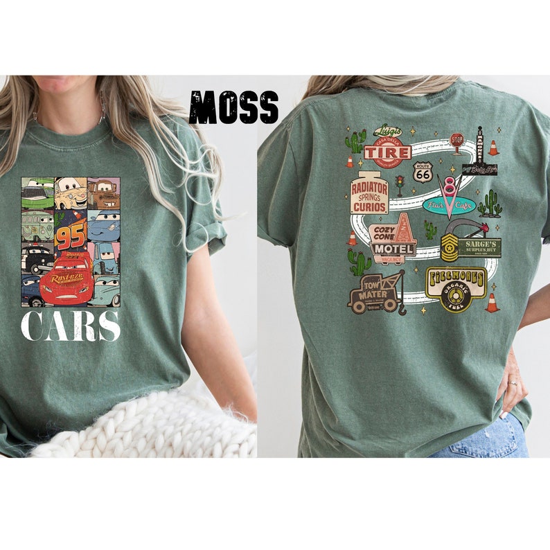 Puede incluir: Una camiseta verde con un estampado de Cars en la parte delantera y un mapa tem&aacute;tico de Cars en la parte posterior. El mapa incluye el texto "Radiator Springs Curios", "Cozy Cone Motel", "Tow Mater" y "Ribbhooks Organic Farms".