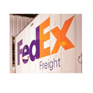 May include: A white FedEx Freight semi-trailer truck with the FedEx logo in purple and orange.