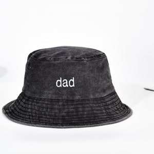 Peut inclure: Un chapeau bob noir avec une finition vieillie et le mot "dad" brodé en blanc sur le devant.