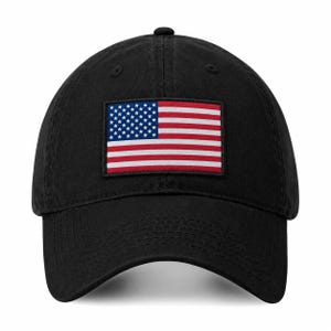 May include: A black baseball cap featuring a rectangular patch on the front panel. The patch displays the United States flag with its characteristic red and white horizontal stripes and a blue canton containing white stars on a black background.