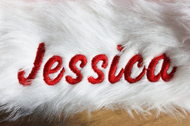 Op de afbeelding: Witte nep bont met de naam "Jessica" geborduurd in rode cursieve letters.