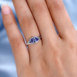 May include: A silver ring with two blue heart-shaped gemstones set in a delicate, curved band.