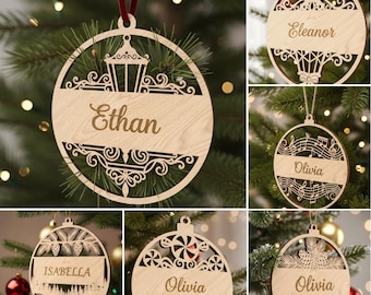 May include: Wooden Christmas ornaments with personalized names, including "Ethan", "Eleanor", "Olivia", and "Isabella". Each ornament features intricate laser-cut designs and is suspended from a red or beige ribbon. The ornaments are displayed on a Christmas tree.