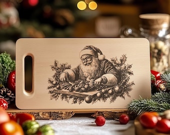 Peut inclure: Une planche à découper en bois avec une poignée présente un motif gravé au laser de Père Noël préparant de la nourriture. Le motif est en noir et blanc et comprend une couronne de verdure et de baies.