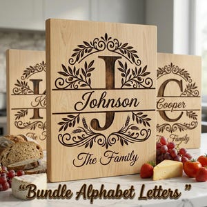 May include: Three rectangular light-coloured wooden cutting boards featuring dark laser-engraved designs. Each board displays a large central letter, a surname, and the text "The Family" surrounded by an intricate olive branch wreath pattern.