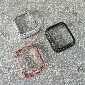 Puede incluir: Tres estuches de reloj de diferentes colores con un diseño decorativo. Los estuches son plateados, negros y de oro rosa.