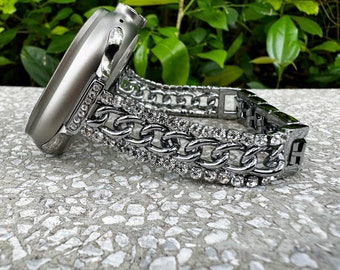 May include: A silver watch band with a chain link design and clear rhinestones. The band is attached to a silver watch case.