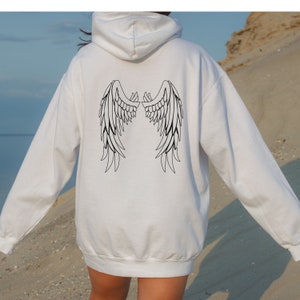 May include: White hooded sweatshirt with a black outline of angel wings on the back.