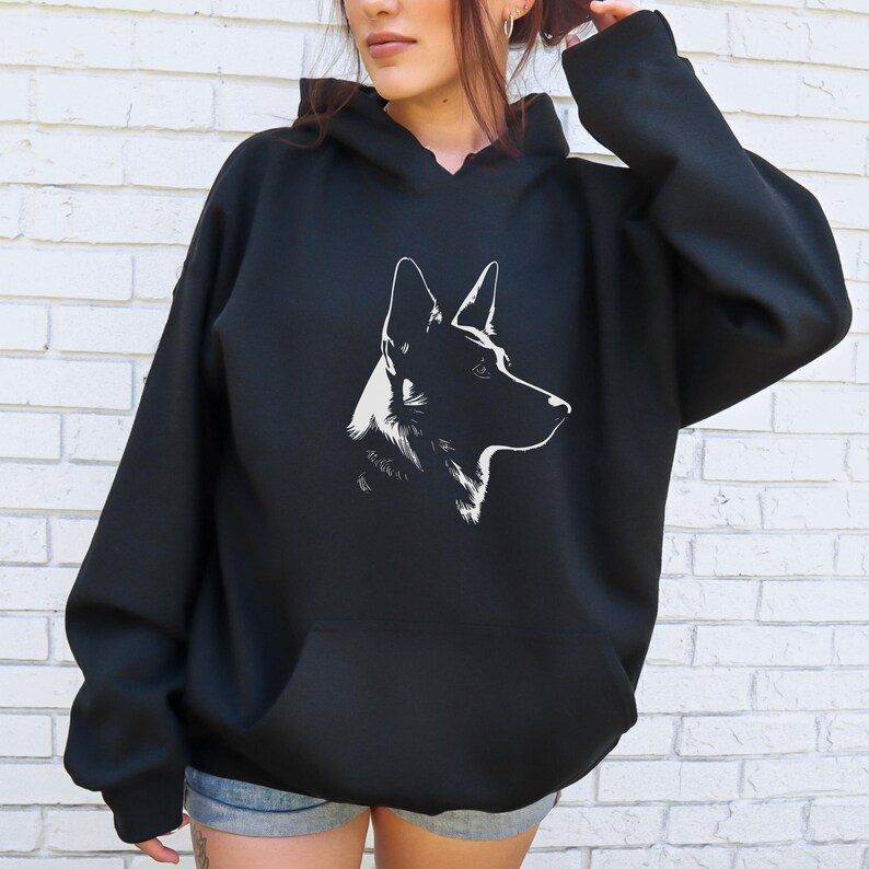 May include: Black hoodie featuring a white graphic of a dog's profile. The dog's head is turned to the right, with its ears and facial features clearly defined. The hoodie has a kangaroo pocket and a hood.