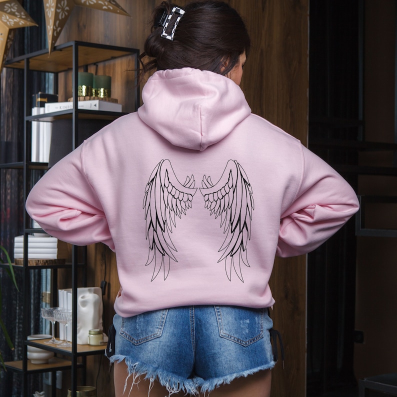 May include: A pink hoodie with a black outline of angel wings on the back.