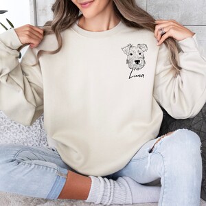 May include: A cream-colored sweatshirt with a black line drawing of a dog's head and the name "Luna" printed on the front.