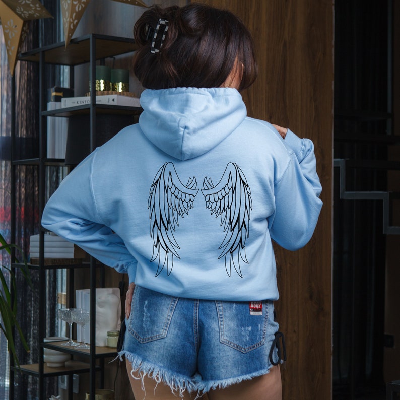 May include: A light blue hoodie with a black outline of angel wings on the back.