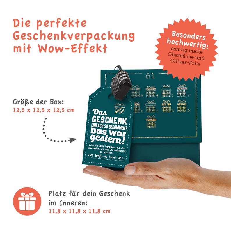 May include: A teal blue gift box with a gold glitter design and a small tag that says "Das Geschenk einfach so bekommen? Das war gestern!" The box is 12.5 cm by 12.5 cm by 12.5 cm. The box is sitting on a hand.