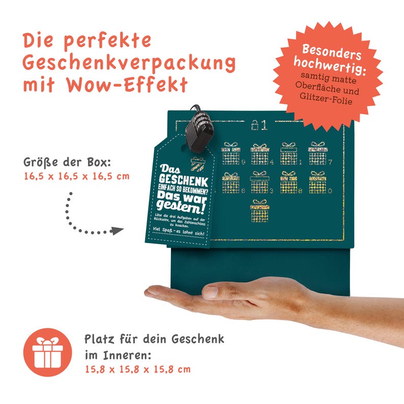 May include: A teal blue gift box with a gold glitter finish and a gold tag that says "Das Geschenk einfach so bekommen? Das war gestern!" The box is 16.5 cm by 16.5 cm by 16.5 cm. The box is sitting on a hand.