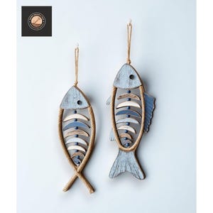 以下が含まれることがあります： 2つの木製の魚の壁の装飾。各魚は薄い青色で、ロープの縁と吊り下げ用のロープのループが付いています。魚には白、青、茶色のアクセントがあります。魚は薄い青色の壁に吊るされています。