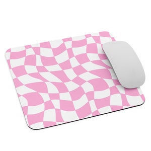 Puede incluir: Alfombrilla de ratón a cuadros rosa y blanco con un patrón ondulado. La alfombrilla de ratón está hecha de un material suave y antideslizante y es perfecta para usar con un ratón de computadora.