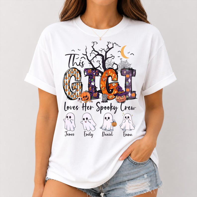 May include: A white t-shirt featuring a graphic with the text "This GIGI Loves Her Spooky Crew". The design includes large letters filled with Halloween patterns, a crescent moon, a tree, and four cartoon ghosts labeled James, Emily, Daniel, and Emma.