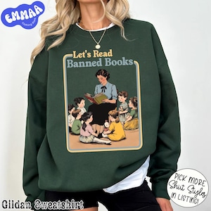 Puede incluir: Sudadera Gildan verde oscuro con la frase "Let's Read Banned Books". El diseño muestra a una maestra leyendo a un grupo de niños. La sudadera tiene el logo "EMMAA Clothing Store" en la esquina superior izquierda.