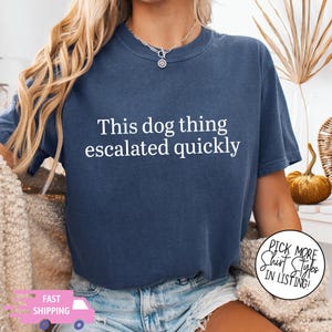 May include: A navy blue short-sleeve t-shirt featuring the white text This dog thing escalated quickly printed on the chest. The shirt has a crew neckline and a relaxed fit, showcasing a solid color design with clear, bold lettering across the front.