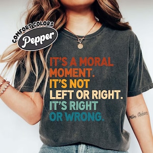 Op de afbeelding: Donkergrijs t-shirt met de tekst "IT'S A MORAL MOMENT. IT'S NOT LEFT OR RIGHT. IT'S RIGHT OR WRONG." in oranje, geel en turquoise. Het shirt heeft een vintage uitstraling en het merk "Pepper" is zichtbaar.