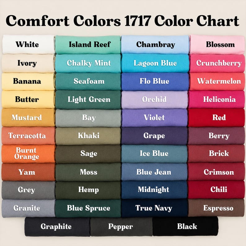 May include: A Comfort Colors 1717 color chart displaying a grid of folded fabric swatches in various shades including white, ivory, yellow, orange, red, pink, purple, blue, green, grey, brown, and black, each labeled with its specific color name.