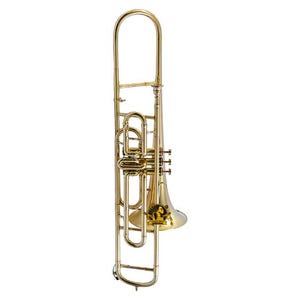 May include: A brass trombone featuring a long slide, a bell, and a series of valves. The instrument has a polished gold-colored finish and includes a circular black and gold logo sticker on the bell with the text "STAGG" visible on the surface.