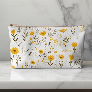 May include: A white zippered pouch with a repeating pattern of yellow flowers and brown stems on a white background.