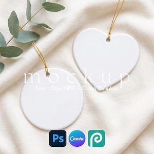 May include: Two blank white ceramic ornaments, one circular and one heart-shaped, each featuring a gold hanging string. The text "mockup" and "Smart Object PSD + Canva Template" is overlaid on the ornaments, accompanied by Photoshop, Canva, and Pinterest icons.