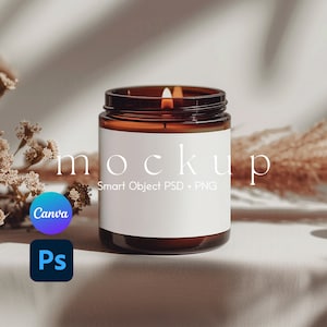 May include: A brown glass candle jar with a white label that says "mockup Smart Object PSD + PNG". The candle is lit and there is a white fabric background.